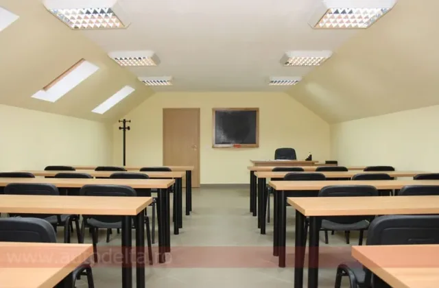 Sală de curs mansardată, cu rânduri de bănci pentru cursanți